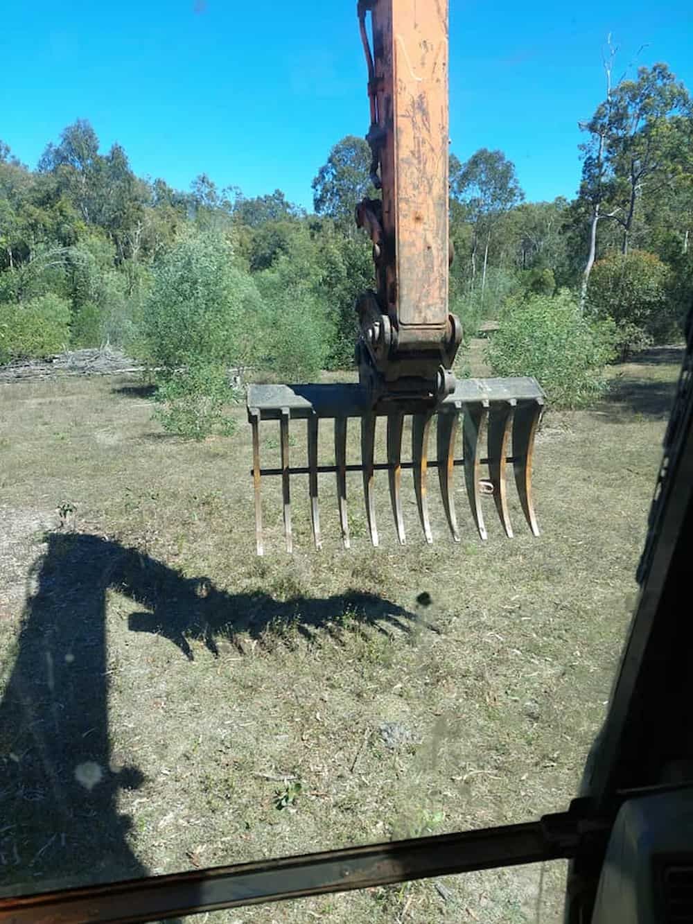A Tractor is Cutting Grass in a Field With Trees in the Background — B E Laser Levelling QLD in Rockhampton, QLD