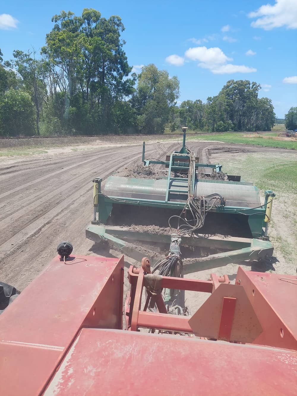A Tractor is Plowing a Field With Trees in the Background — B E Laser Levelling QLD in Hervey Bay, QLD