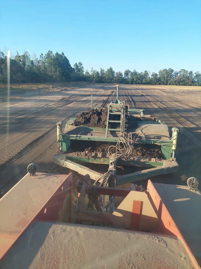 A Tractor is Pulling a Trailer Full of Dirt in a Field — B E Laser Levelling QLD in Bucca, QLD