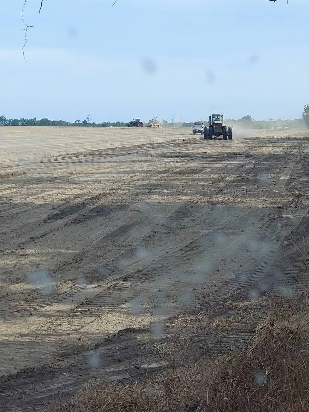 A Tractor is Plowing a Field on a Sunny Day — B E Laser Levelling QLD in Bucca, QLD