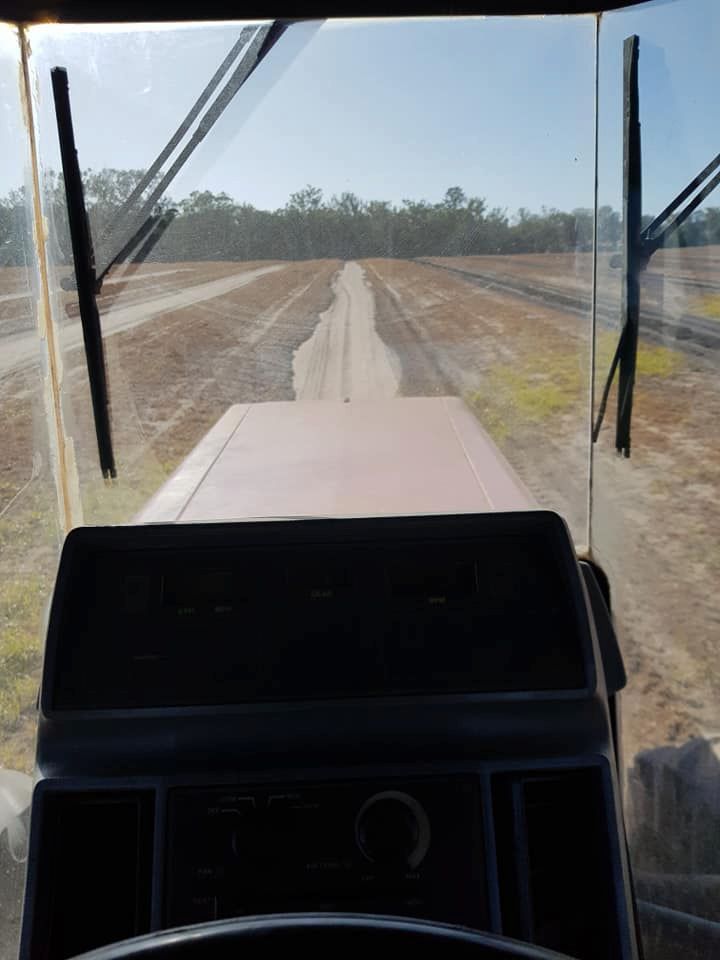 A Person is Driving a Tractor Down a Dirt Road — B E Laser Levelling QLD in Rockhampton, QLD