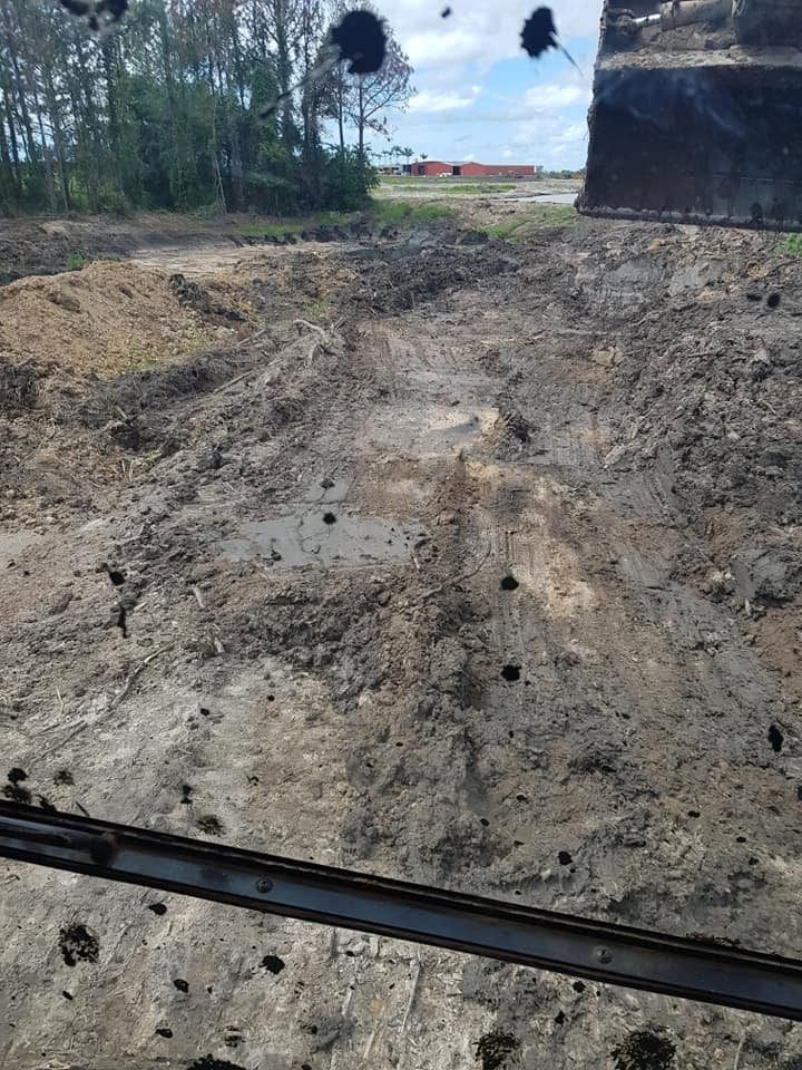 A Bulldozer is Driving Through a Muddy Field — B E Laser Levelling QLD in Rockhampton, QLD