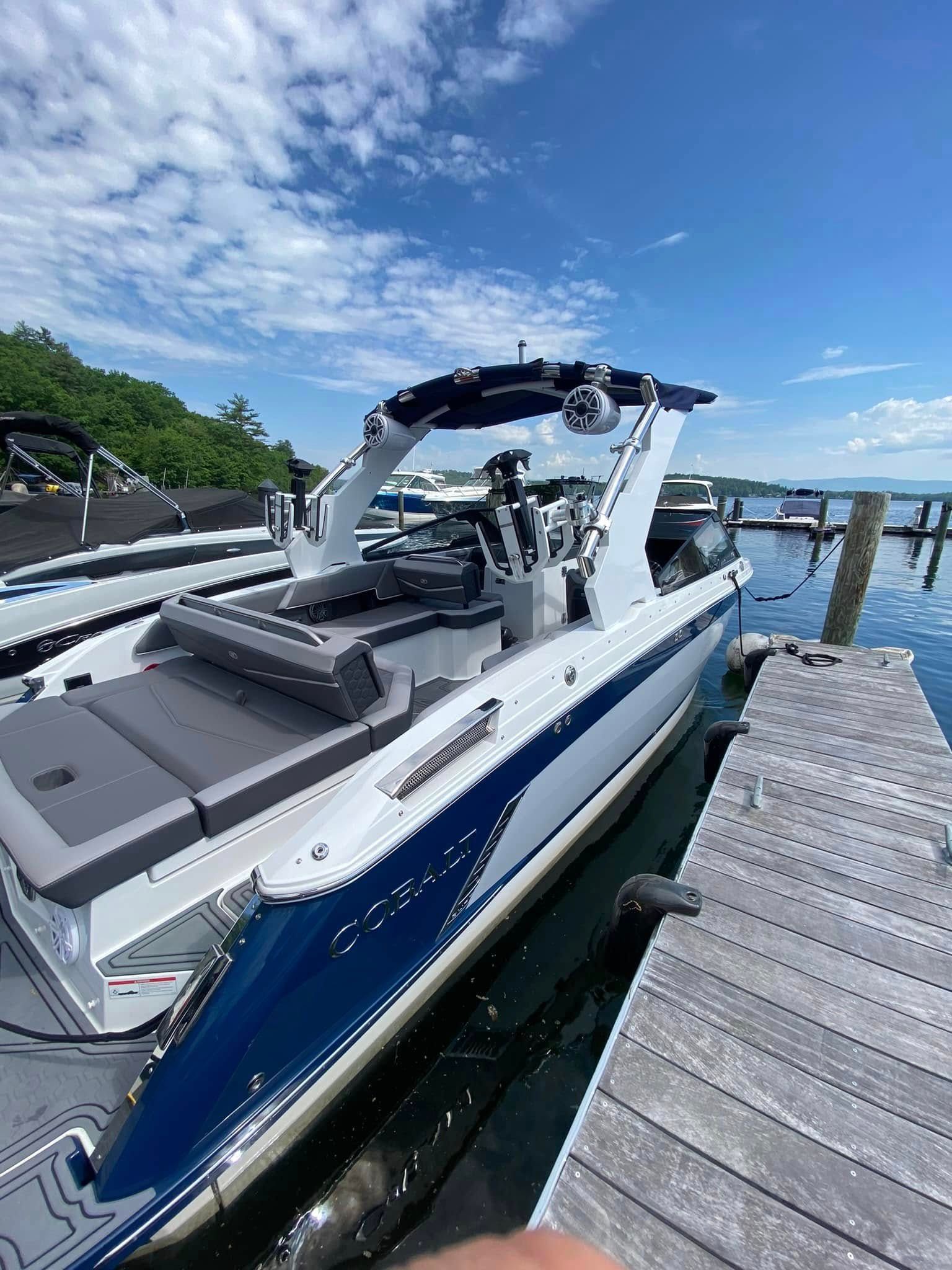 White and blue speedboat docked beside a wooden pier on a sunny day