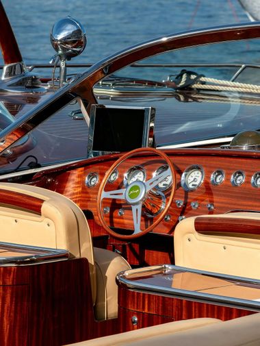 Wooden luxury boat cockpit with polished steering wheel and gauges on the water