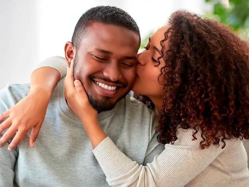 A woman is kissing a man on the cheek.