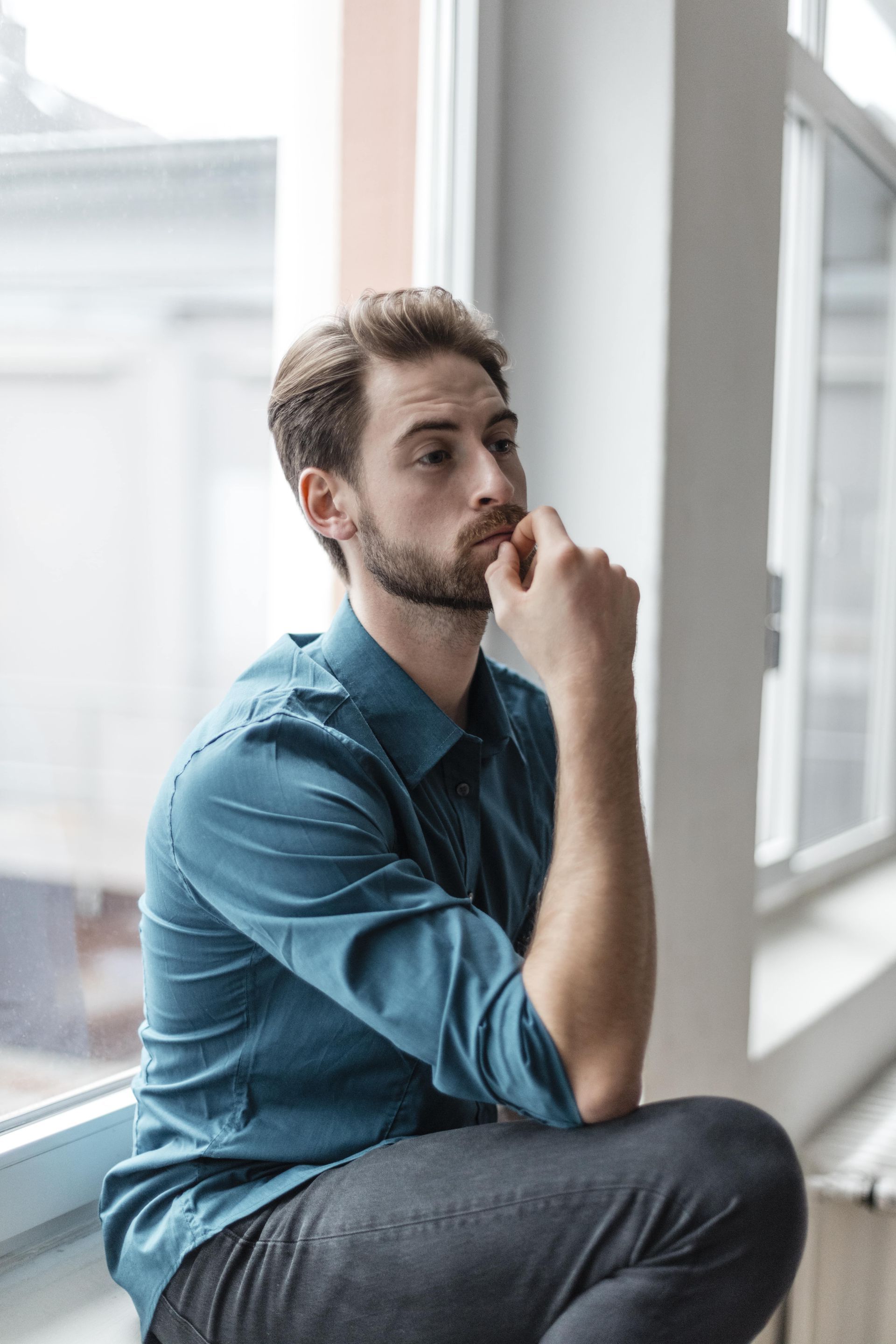 A man in a military uniform is sitting in a wheelchair holding his head.