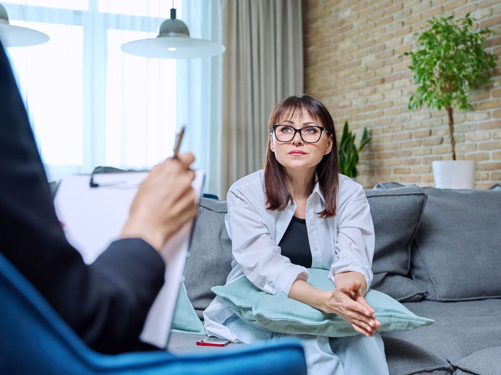 A woman wearing headphones is smiling while sitting on a couch.