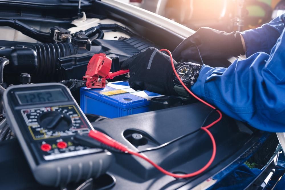 A Mechanic Is Working On A Car Battery With A Multimeter — Dancers Car Care In Ballina, NSW