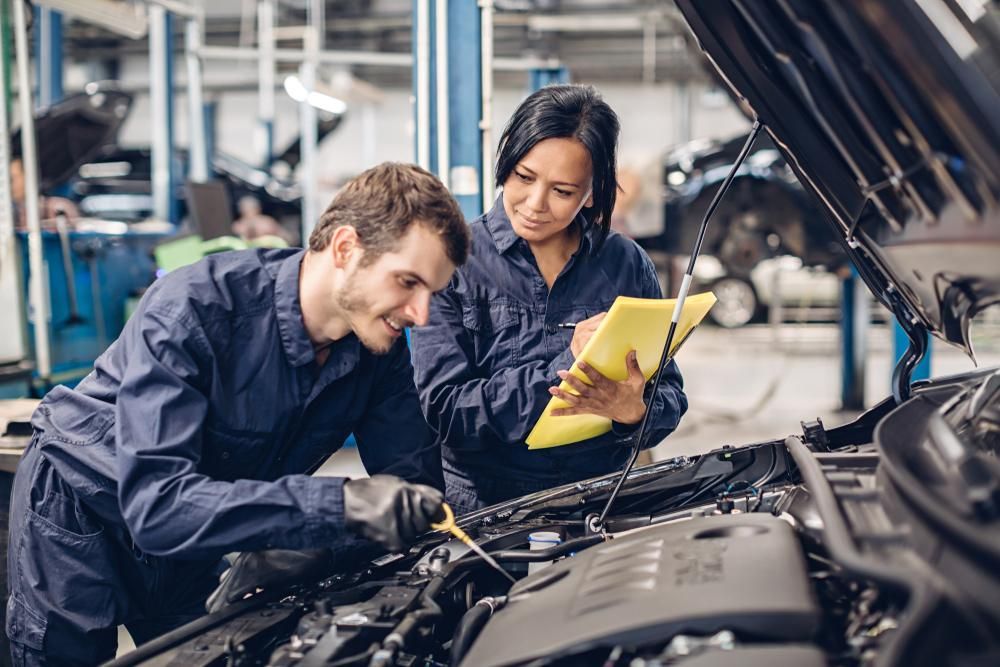 A Man And A Woman Are Working On A Car In A Garage — Dancers Car Care In Ballina, NSW