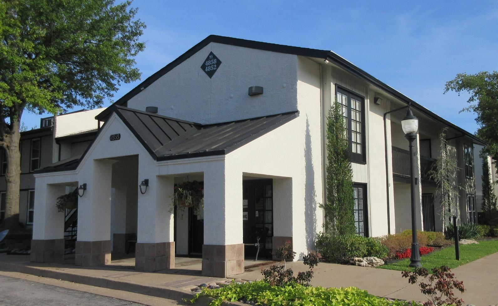 A large white apartment building with a black roof