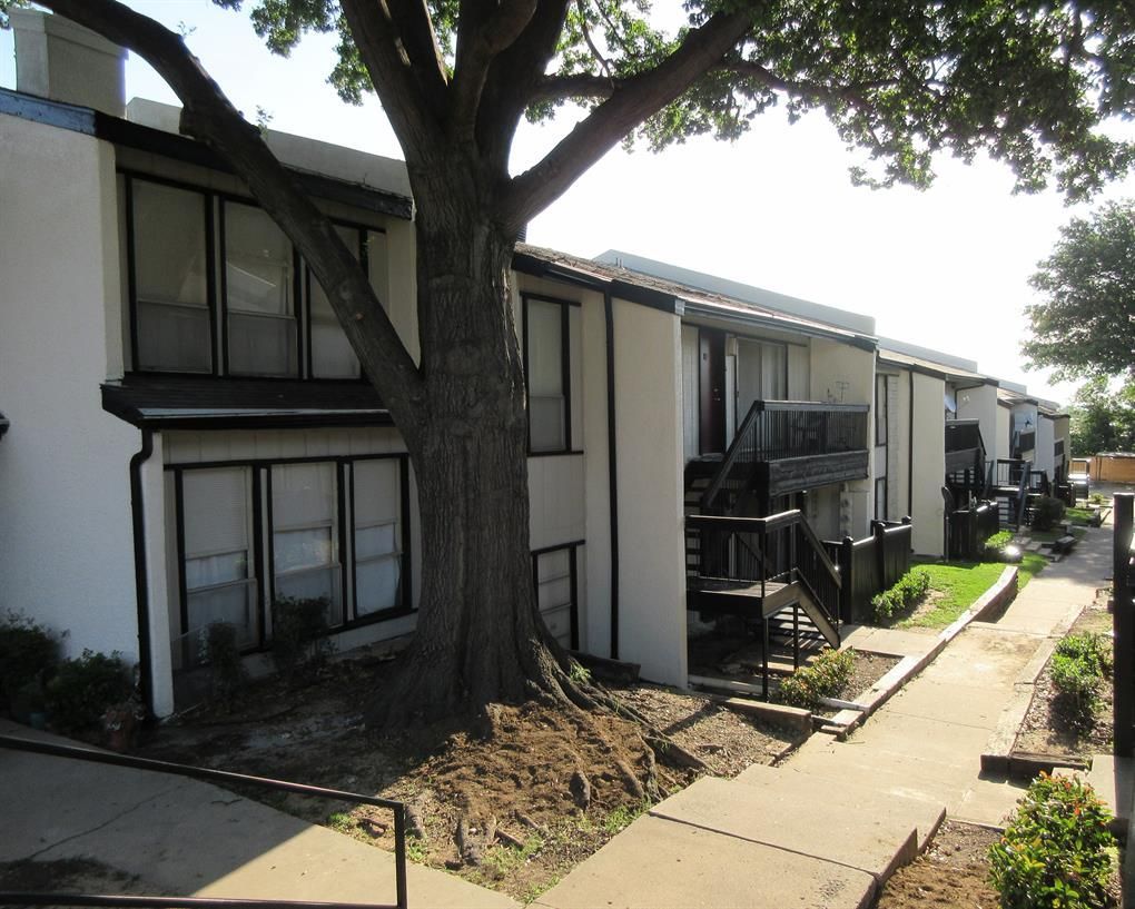 A white apartment building with a tree in front of it