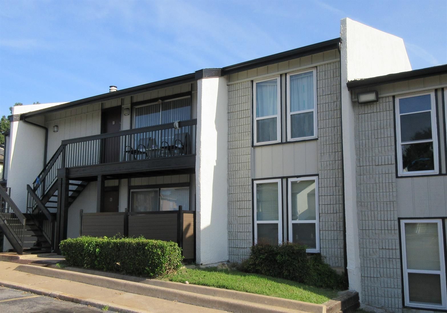 A white apartment building with a balcony and stairs
