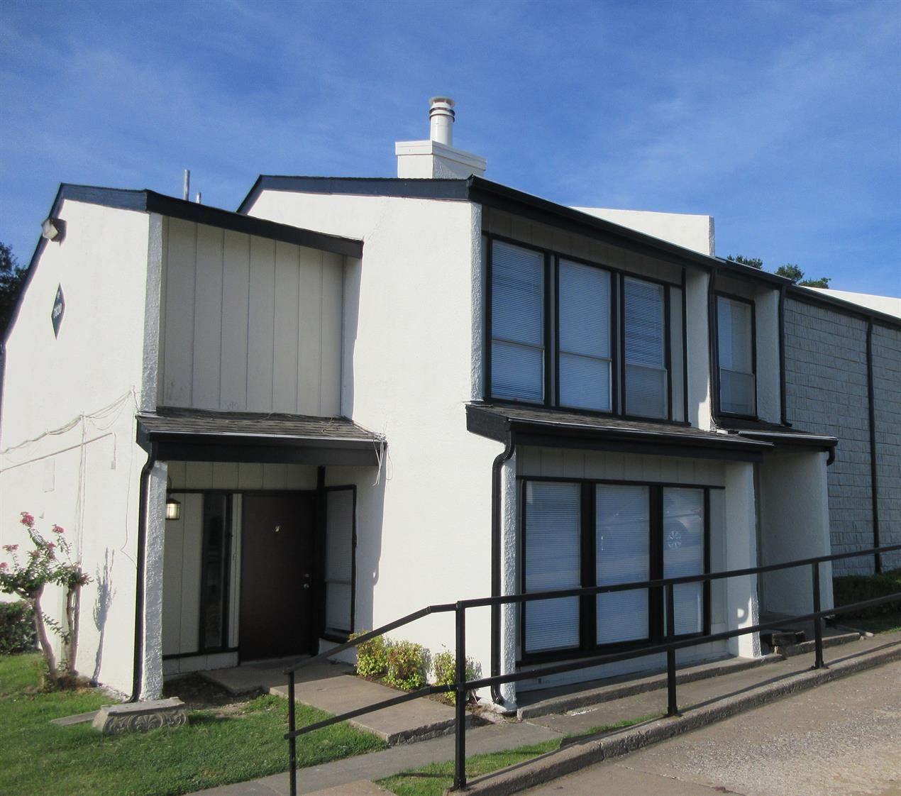 A white house with a black railing and a blue sky in the background