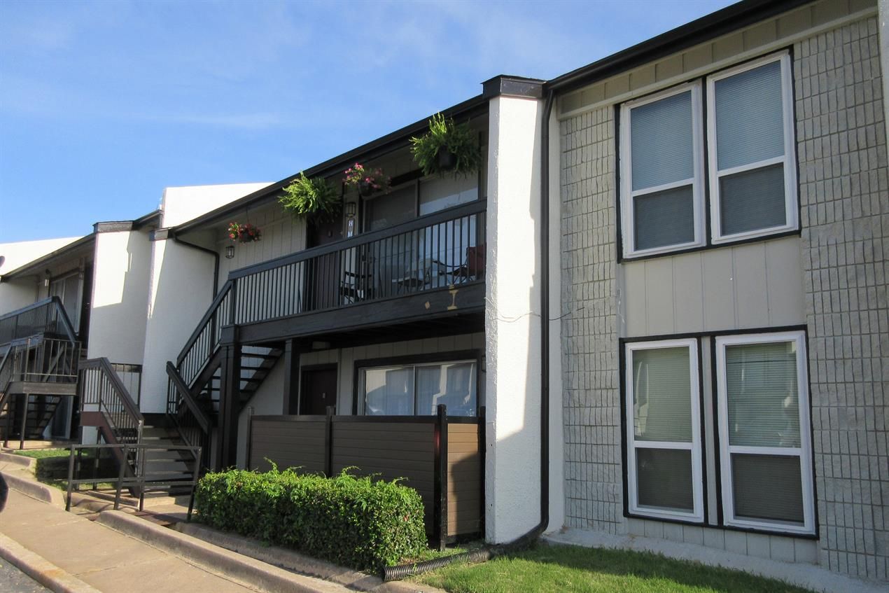 A white apartment building with a balcony and stairs