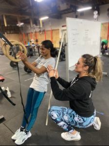 A woman is helping another woman do exercises in a gym.