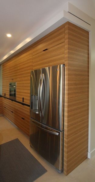 A stainless steel refrigerator in a kitchen with wooden cabinets