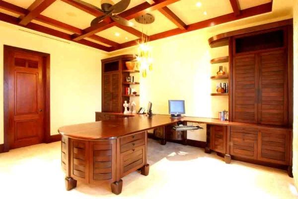 A wooden desk with a computer on it in a room with a ceiling fan