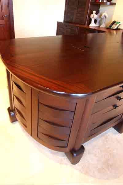 A large wooden desk with drawers and a curved top