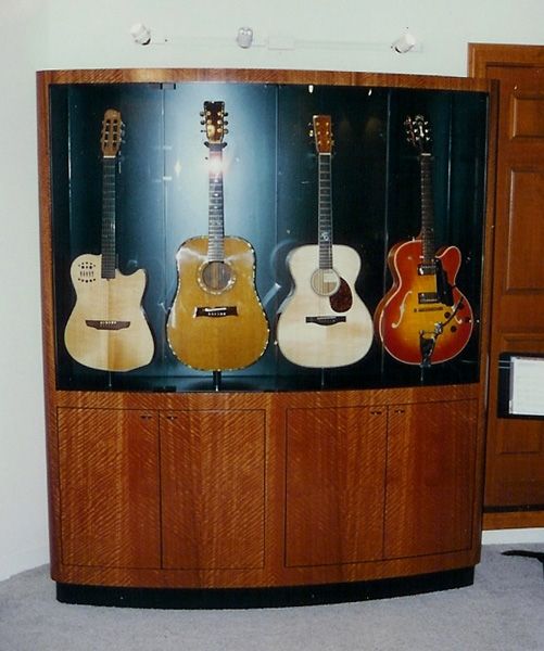 Four guitars are displayed in a glass case