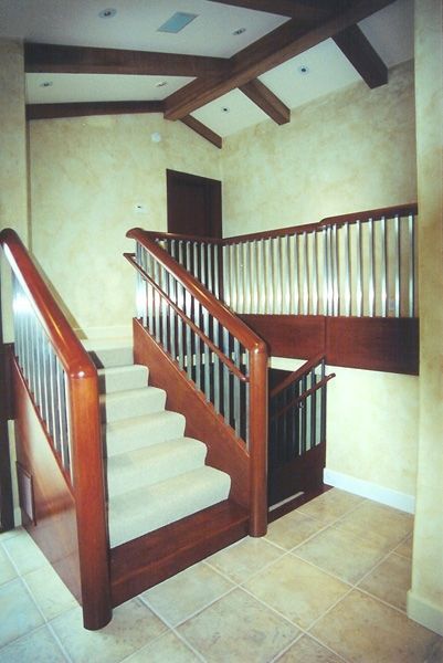 A wooden staircase with a metal railing and carpeted steps