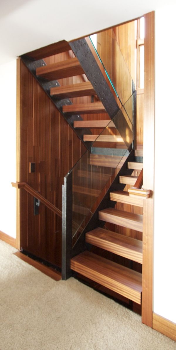 A wooden staircase with a glass railing in a hallway