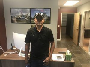Woman in yellow hard hat and green safety vest against a green background.