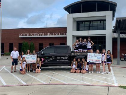 North Forsyth High School cheerleaders with a truck and checks.
