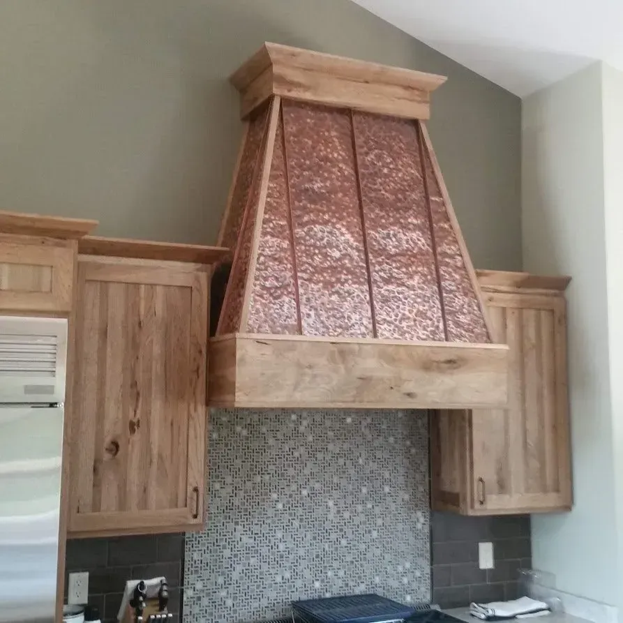 Copper range hood with wood trim in a kitchen.