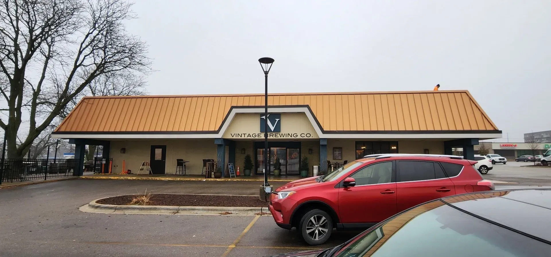 Exterior view of a building with a red car parked in front. Cloudy day, parking lot. Exterior view of a building with a red car parked in front. Cloudy day, parking lot.