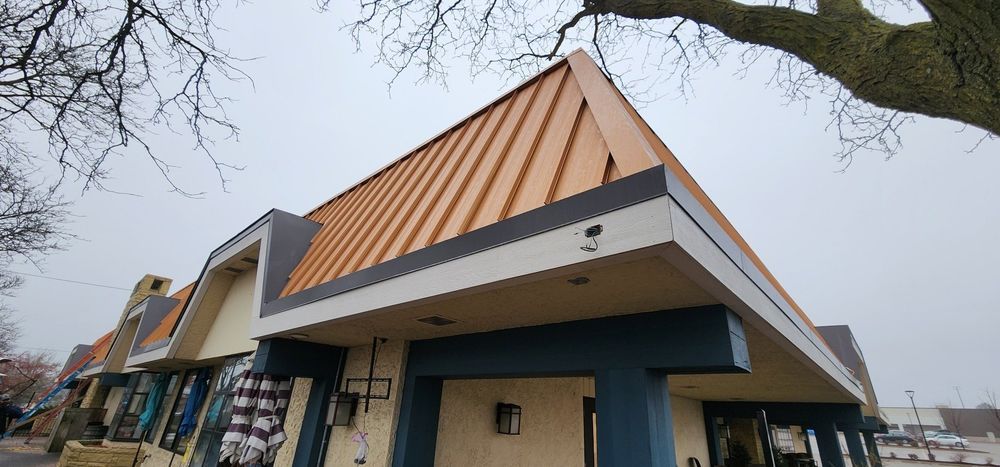 Buildings with copper-colored roofs and blue and white trim under an overcast sky.