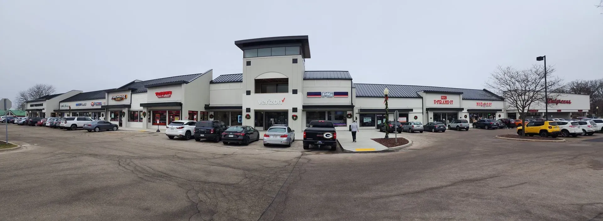Shops in a strip mall, parked cars, gray overcast sky. Shops in a strip mall, parked cars, gray overcast sky.