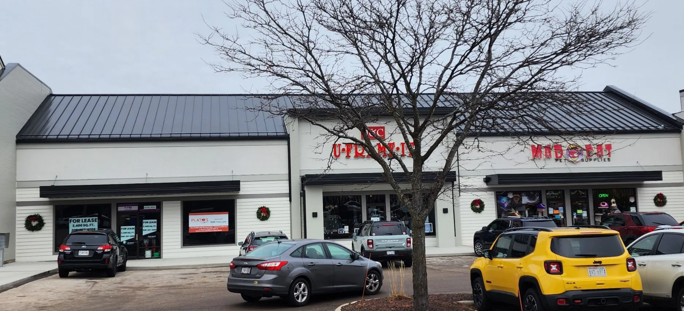 Exterior of a restaurant with a black roof and white walls. Cars parked out front.