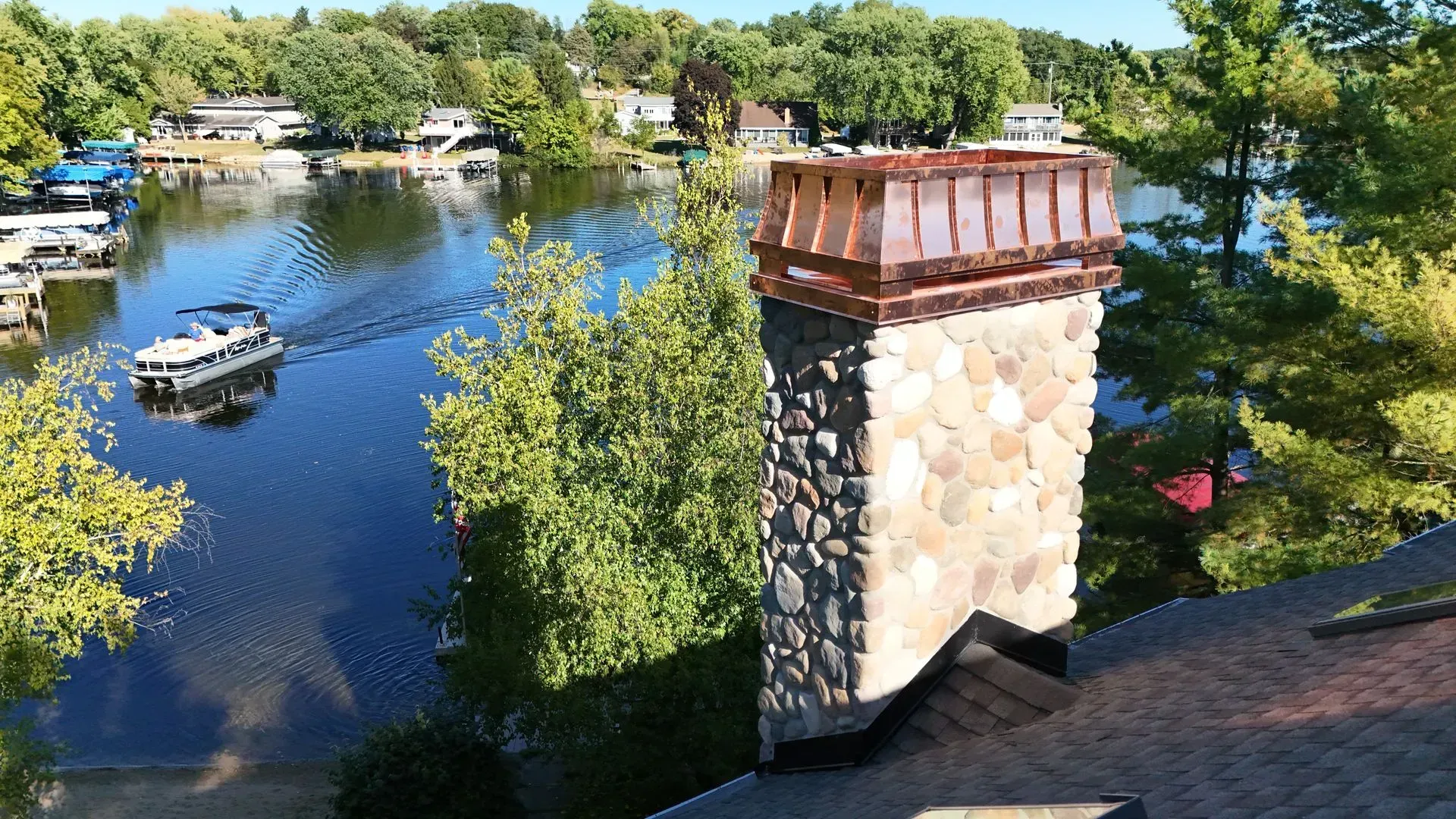 Stone chimney on a rooftop overlooking a lake with a boat.
