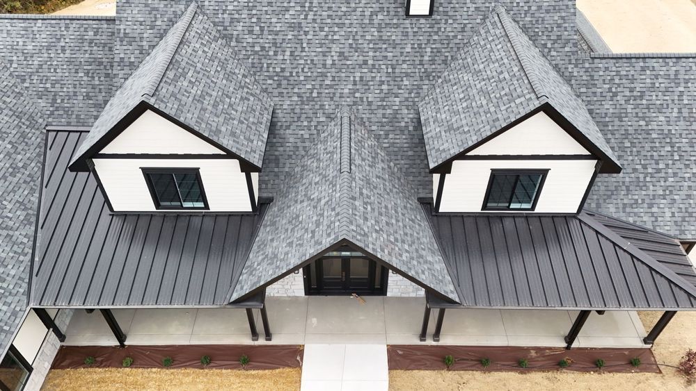 Gray roof with three dormers, black trim, and white siding on a house.