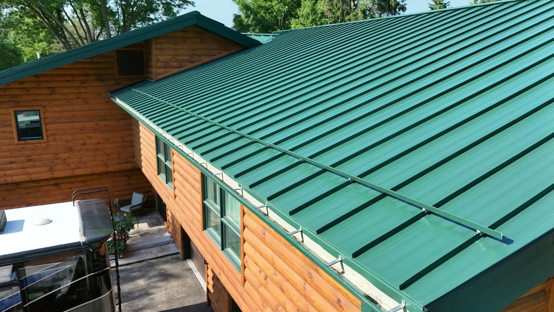 Green metal roof on a wooden cabin. Guttering along the edge.