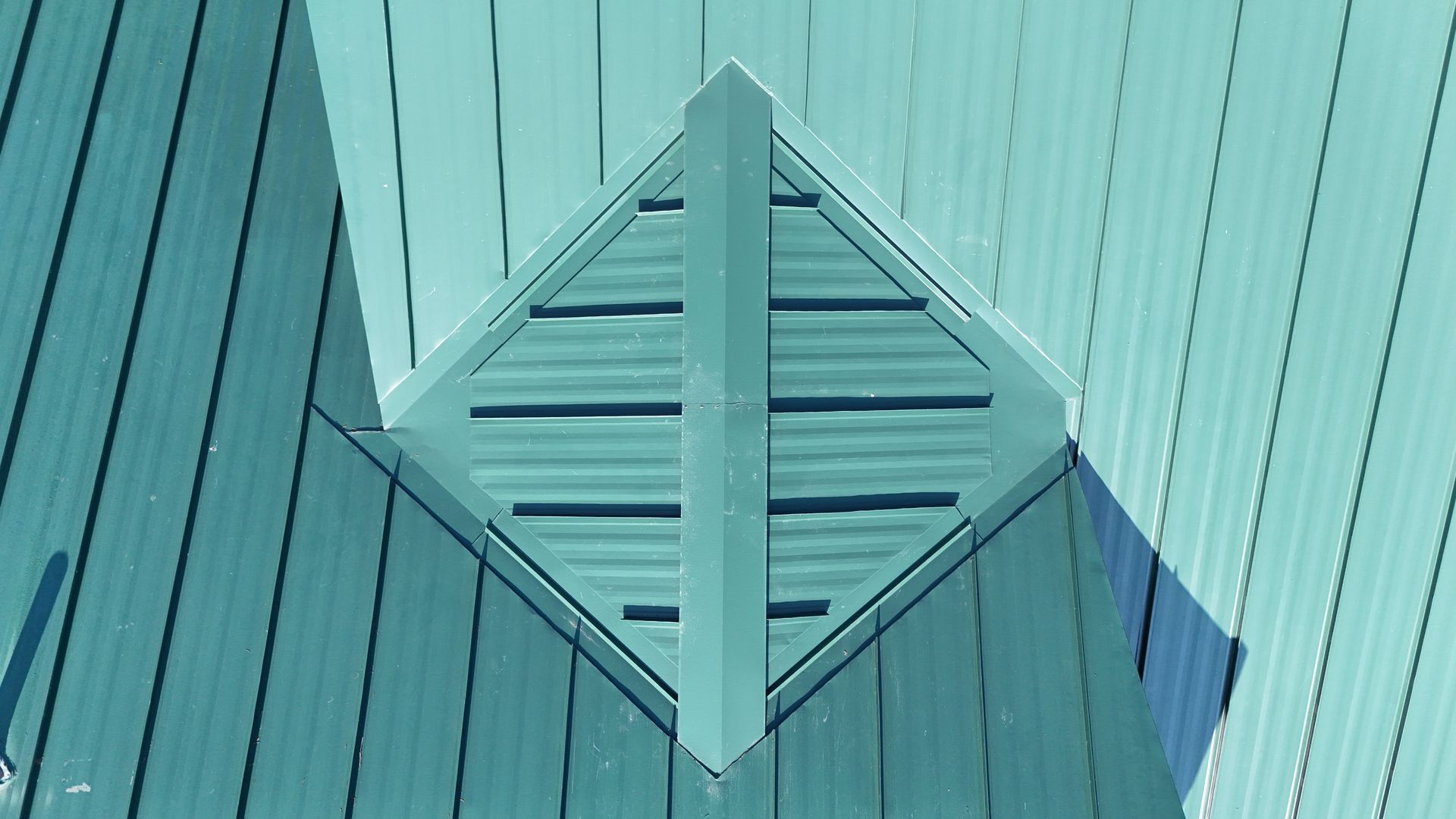 Teal metal roof with a diamond-shaped vent.