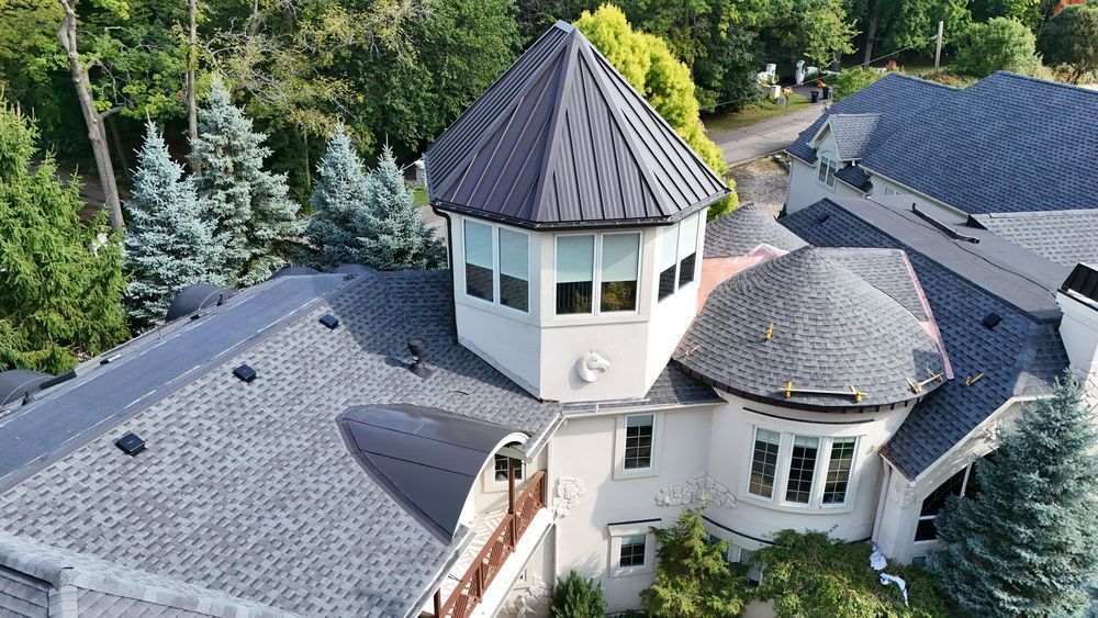 Overhead view of a house with a gray roof and a central tower with a black cone-shaped roof.