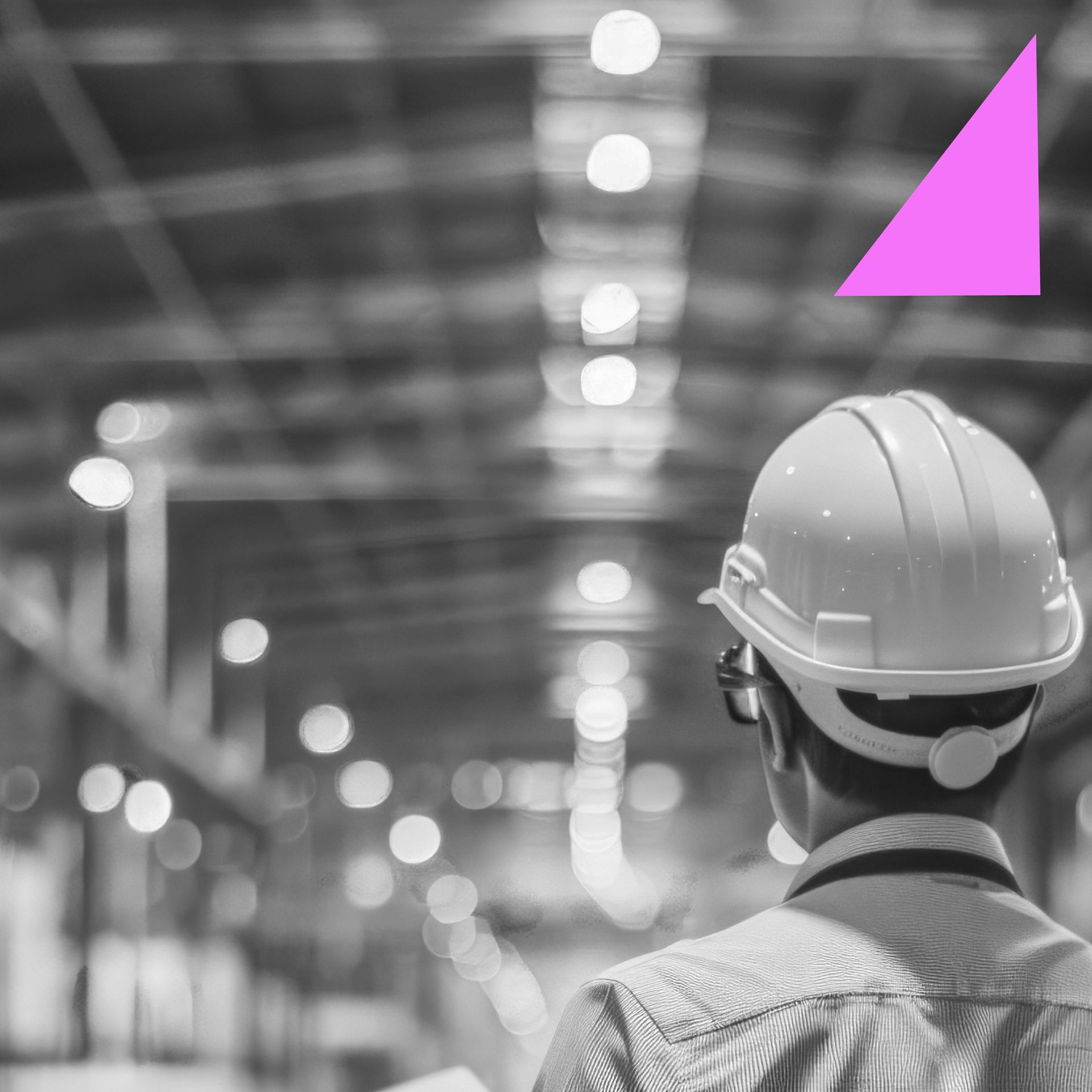 Construction worker wearing a white hard hat, looking toward a factory, with a pink triangle.