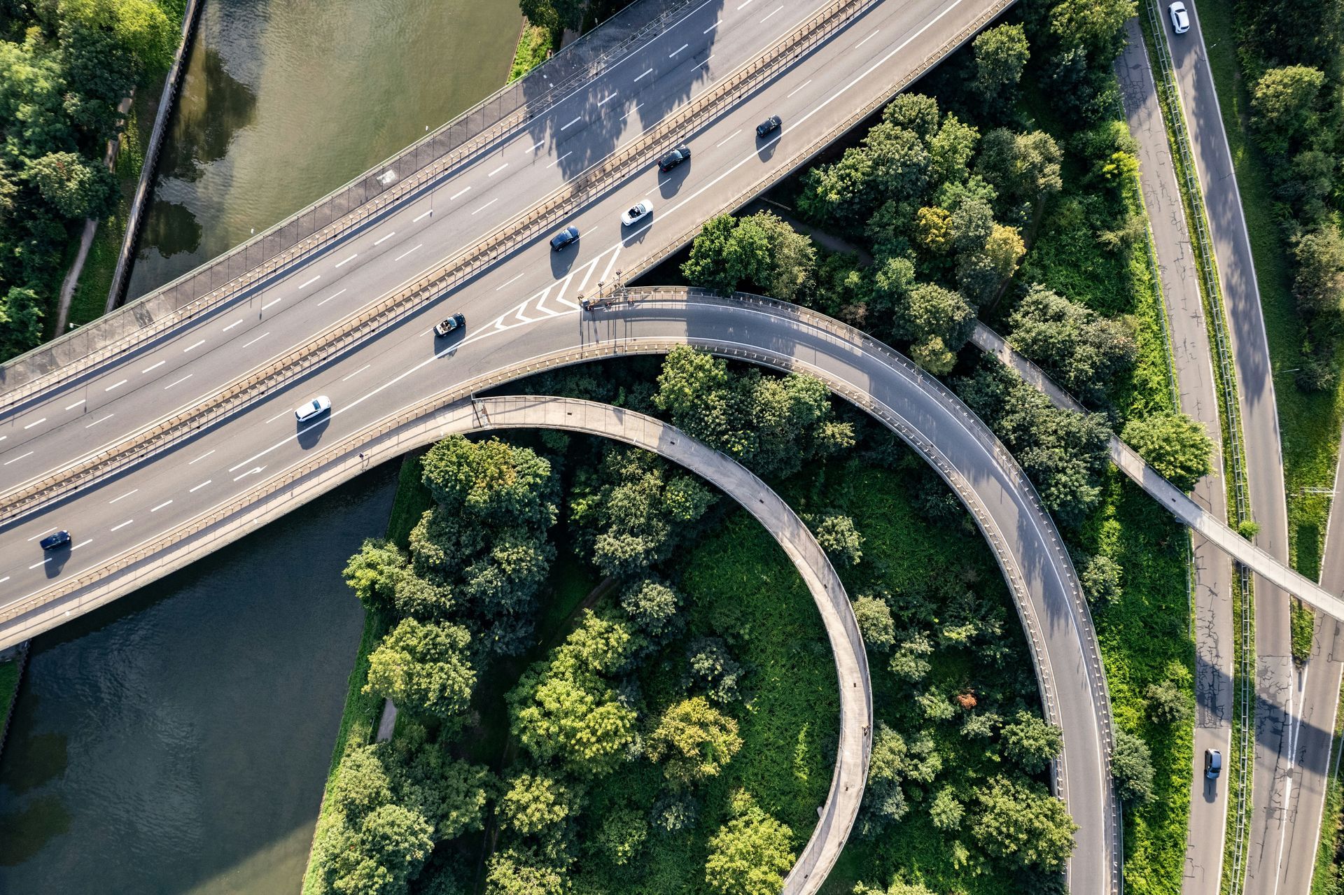 Aerial view of highway interchange. Cars travel on curving roads through trees.