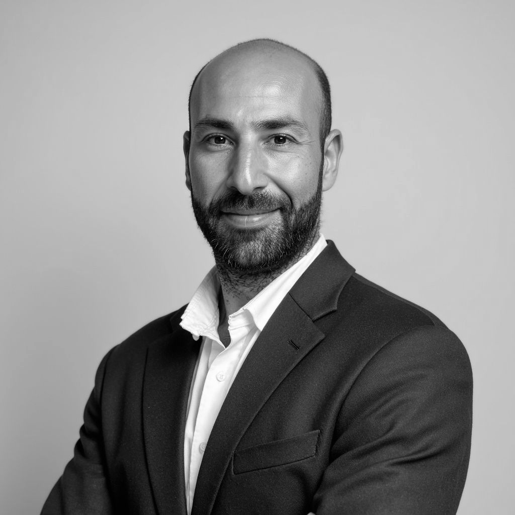 Person in hard hat looking at a factory interior, with pink triangle overlaid in the upper right.