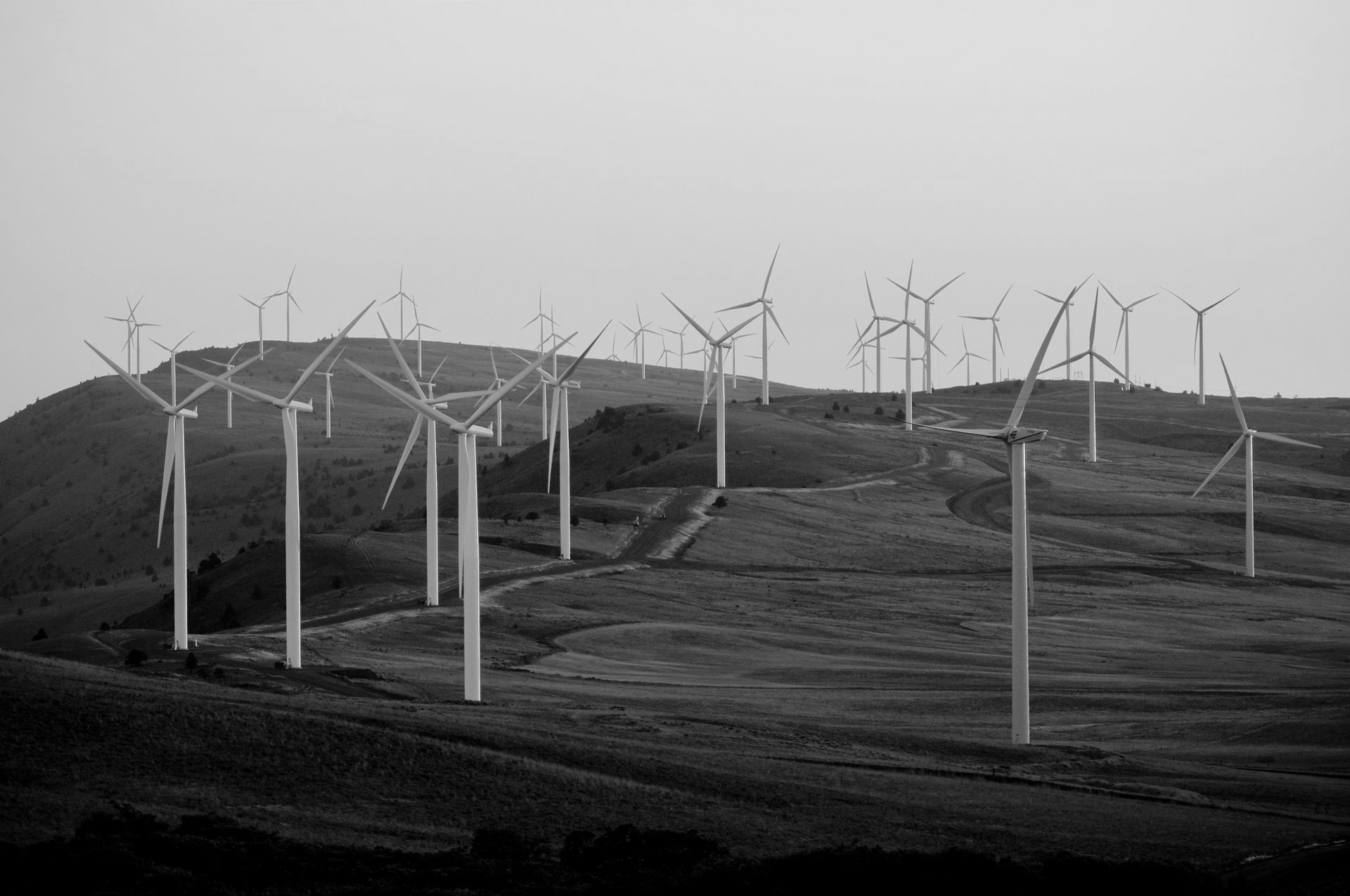 Wind turbines on a grassy hilltop at sunset.