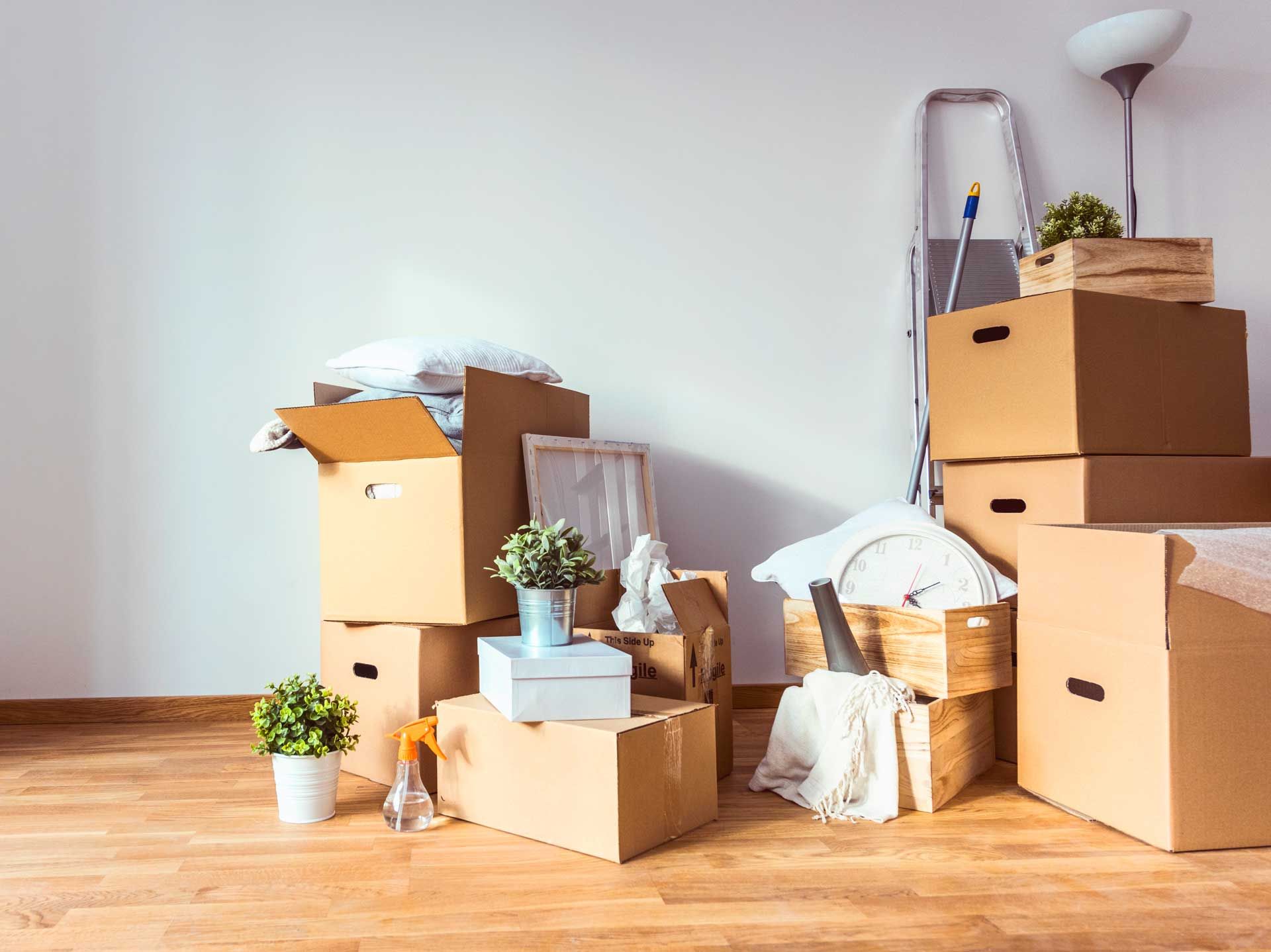 Cardboard boxes stacked in a room with a ladder and lamp, signifying a move.