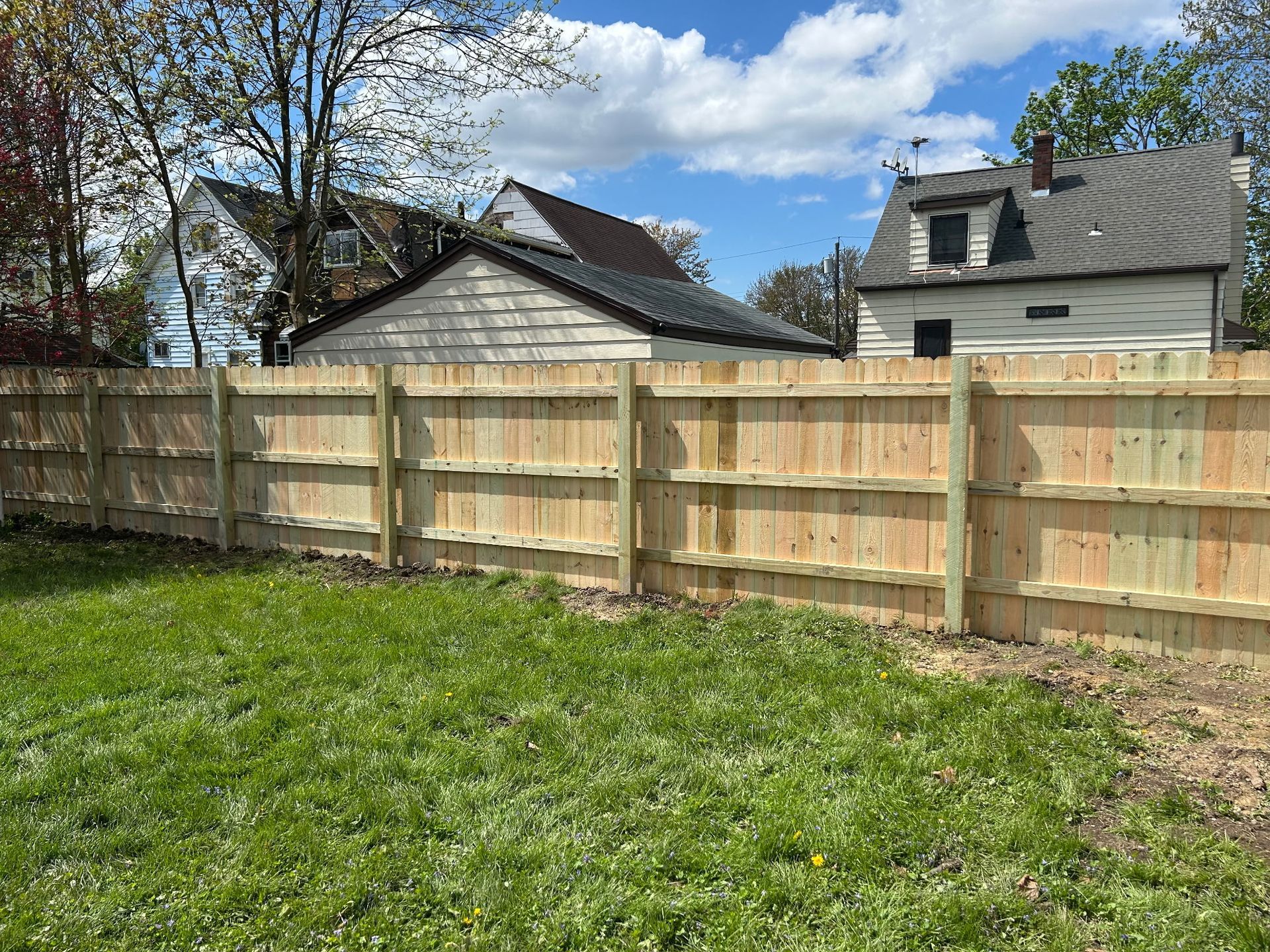 A white fence with a gate is in front of a house.
