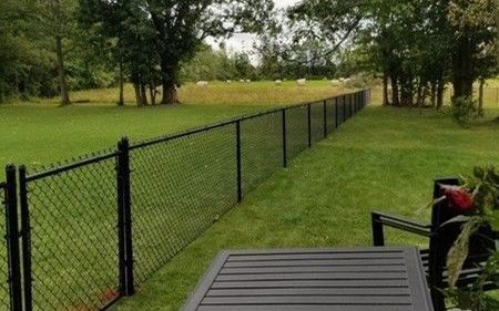 White vinyl picket fence installed around a yard beside a single-story house.