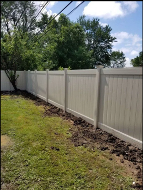 White vinyl privacy fence lining a backyard with grass.
