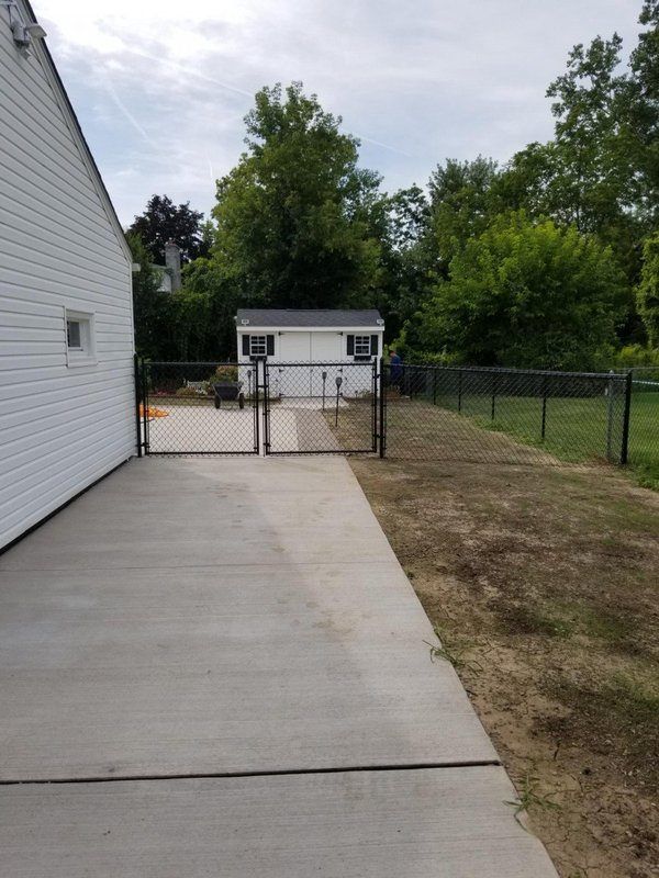 A concrete driveway leading to a shed and a white house