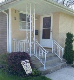 White porch with steps, railings, and a front door. A sign reads White porch with steps, railings, and a front door. A sign reads