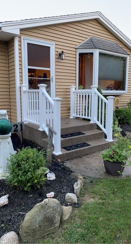 A mobile home with a porch and stairs in front of it.