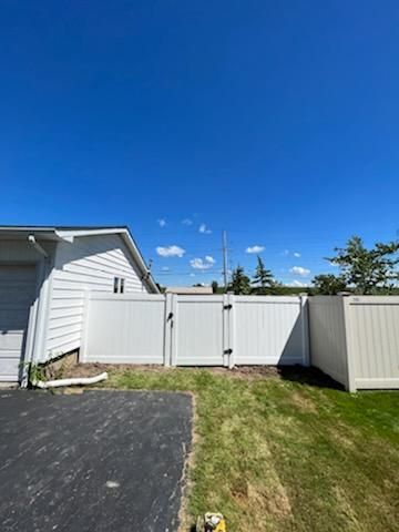 There is a white fence in the backyard of a house.