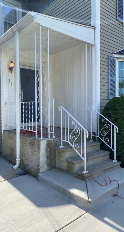 A white porch with stairs leading up to it and a white railing.
